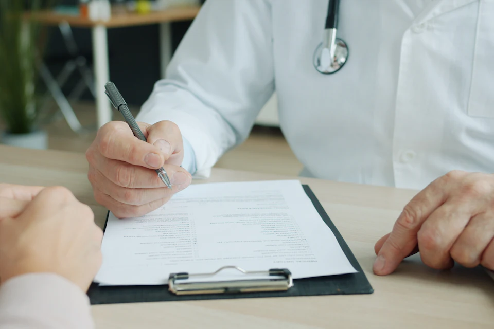 Médico escribiendo en el informe de un paciente
