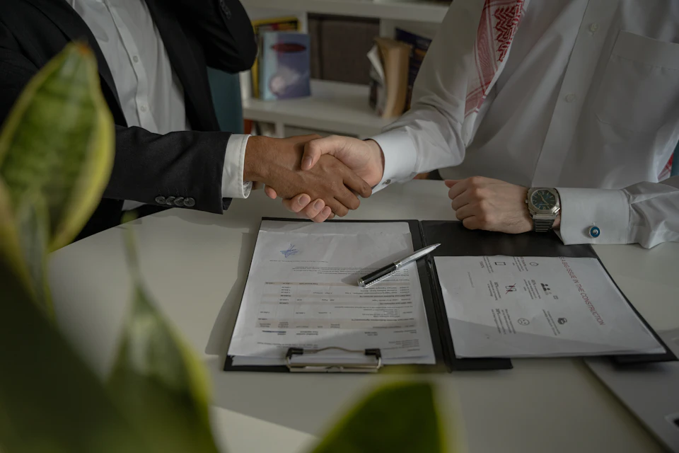 Dos personas se dan la mano sobre un documento